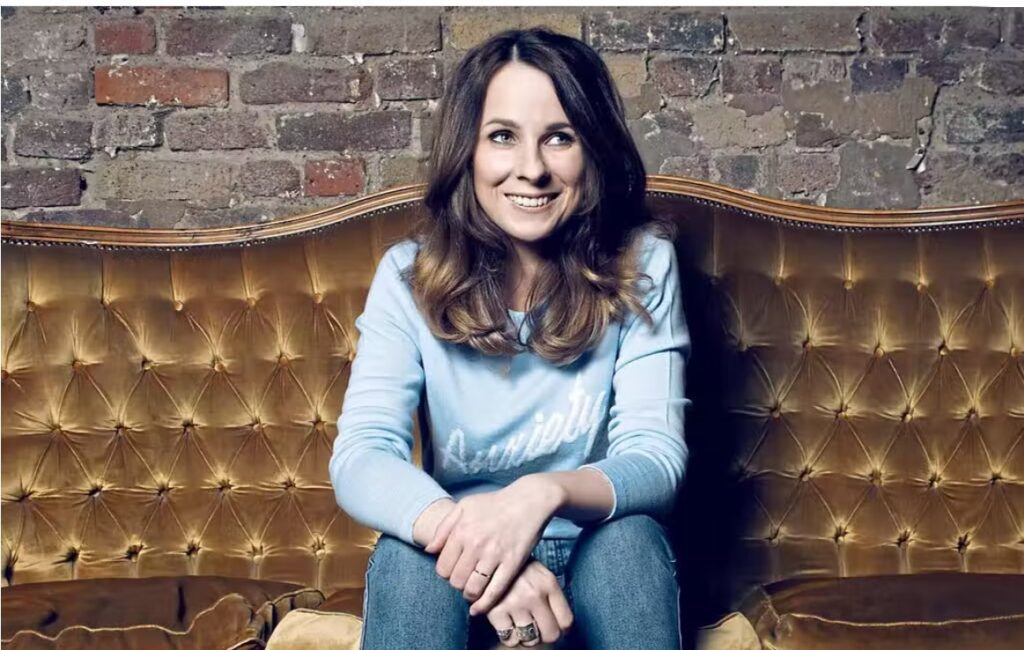 Griefcast podcaster cariad lloyd sitting on couch.