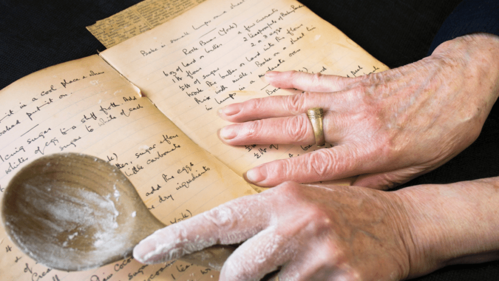 woman holding spoon covered with flour consulting handwritten family recipe