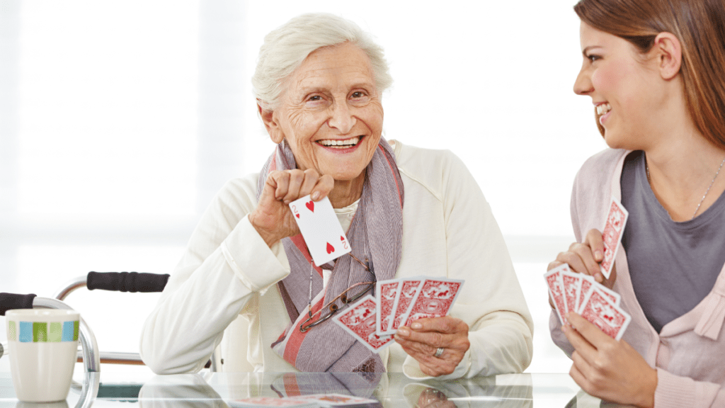 Older woman playing cards and laughing with younger woman.
