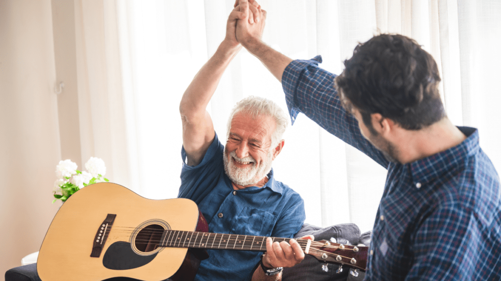 older man holding guitar hi-fiving a younger man