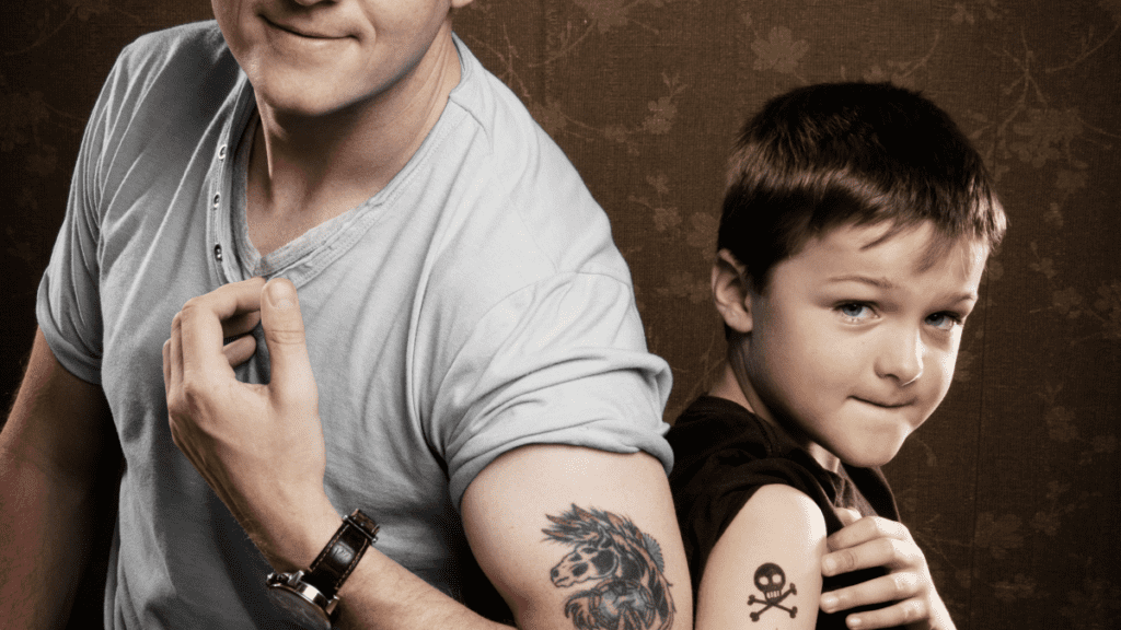 Man and boy showing off tattoos on their upper arms.