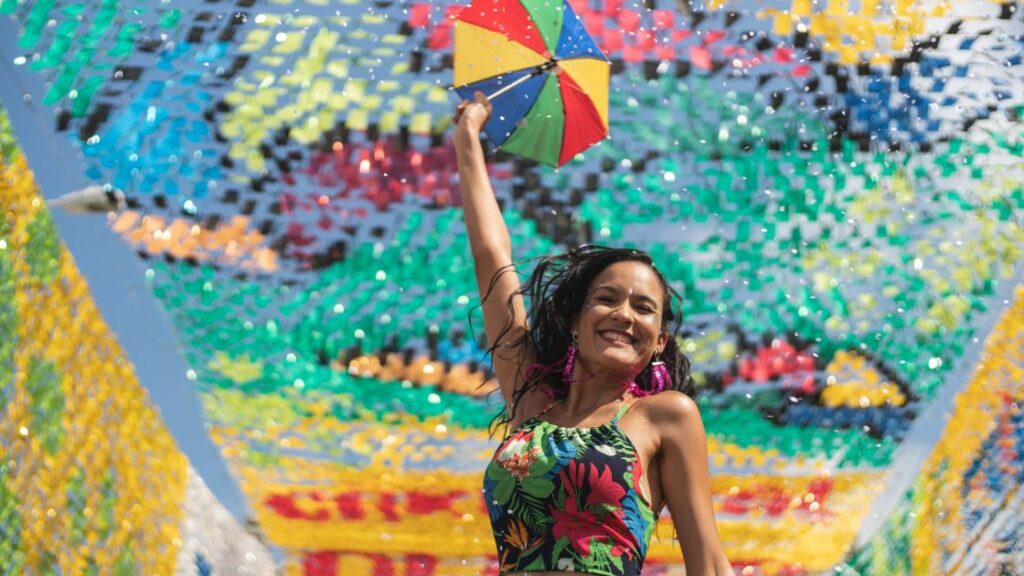 young woman holding a small multi-colored umbrella while doing a dance popular in Brazil
