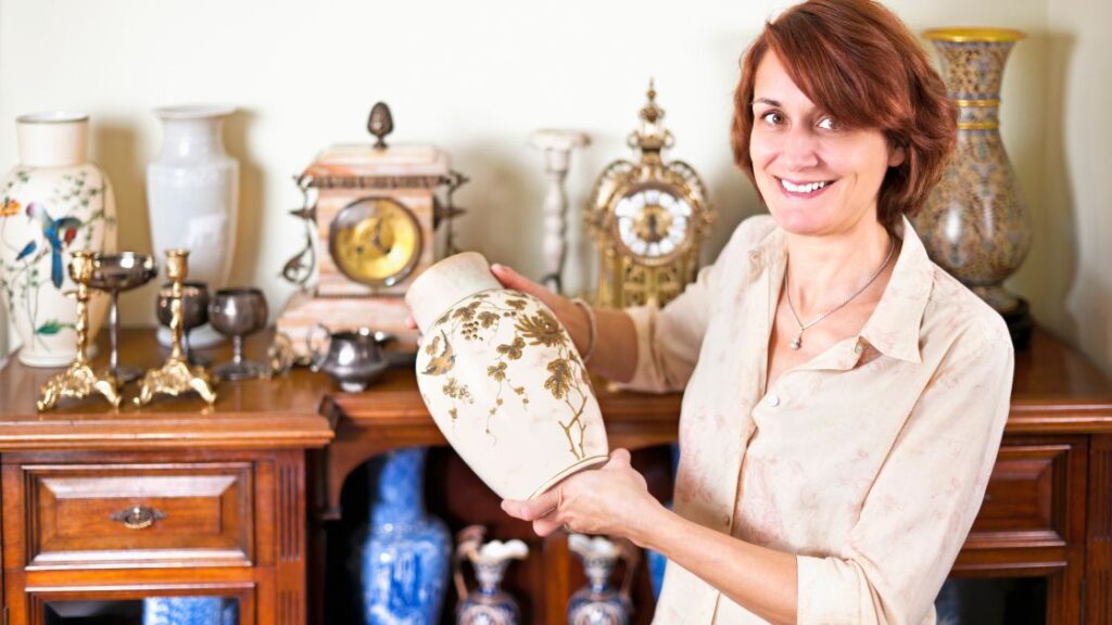 Woman holding a vase amid other family antiques.