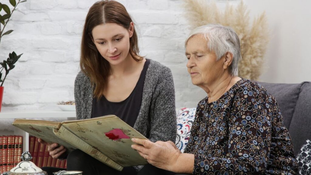 Young woman looking at an old book with an older woman.